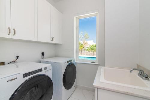 a white laundry room with a washing machine and a sink at Luxurious 4 Bedroom Home on Seven Mile Corridor in the Heart of Cayman with a Private Pool in Seven Mile Beach