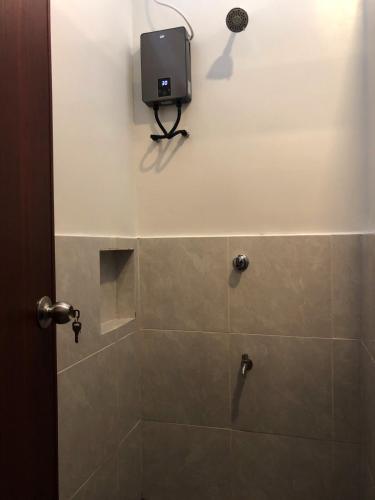 a bathroom with a shower with a tv on the wall at Cafe Moto Hostel in Puerto Princesa City