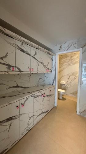 a bathroom with a marble wall with a toilet at Flat 3 suites frente mar in Florianópolis