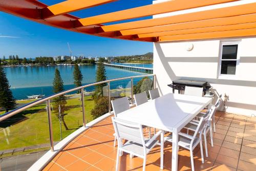 a white table and chairs on a balcony with a view of the water at Sunrise Penthouse in Tuncurry