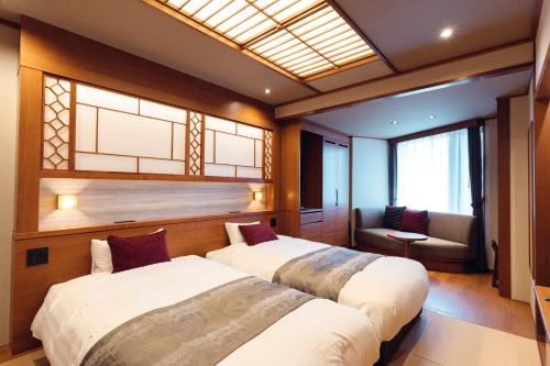 two beds in a room with a couch and a window at Hanabishi Hotel in Hakodate