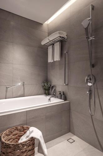 a bathroom with a bath tub and a shower at Fraser Residence Hanoi in Hanoi
