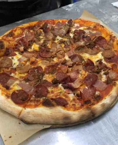 a pepperoni pizza sitting on top of a table at Cafe Moto Hostel in Puerto Princesa City