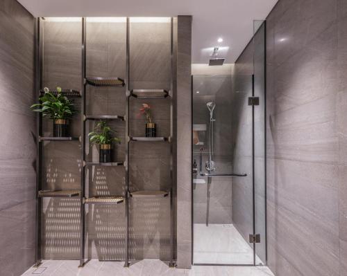 a shower with a glass door with plants on the shelves at Fraser Residence Hanoi in Hanoi