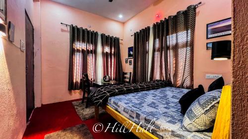 a bedroom with a bed and windows with curtains at Hill Halt in Hawālbāgh