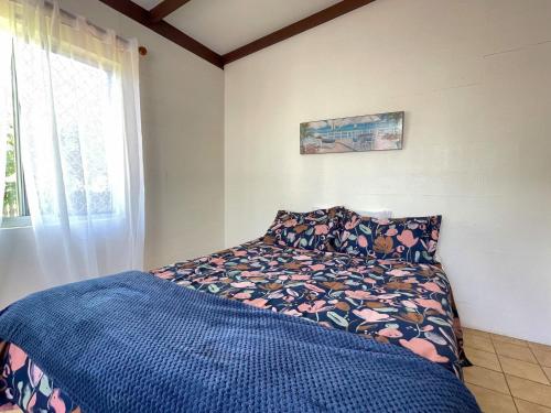 a bedroom with a bed with a blue blanket and a window at Moonshadow-Burrum Heads- Beachfront- 3BR- Water Views in Burrum Heads