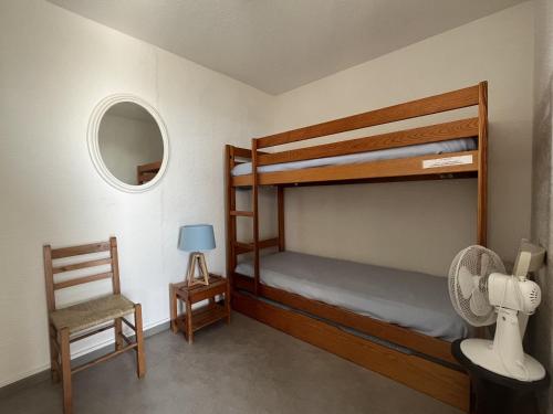 - une chambre avec 2 lits superposés et une chaise dans l'établissement Le Barcarès: T2 moderne climatisé, au bord de mer, 4 pers, parking sécurisé - FR-1-799-4, au Barcarès