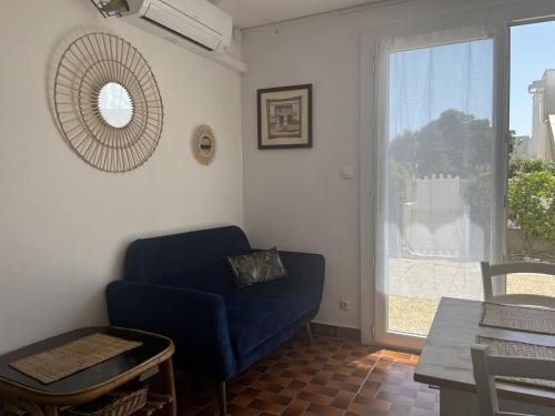 un salon avec un canapé bleu et une fenêtre dans l'établissement T3 Rénové Climatisé RDJ - Proche Plage - Parking - Animaux OK - FR-1-799-5, au Barcarès