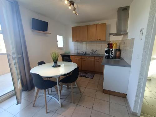 une cuisine avec une table et des chaises dans une cuisine dans l'établissement T2 Mezzanine Climatisé avec Terrasse - 5 Pers. Près Plage et Parc des Dosses - Parking Inclus - FR-1-799-17, au Barcarès
