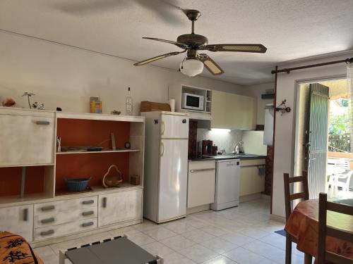 Il comprend une cuisine équipée d'un réfrigérateur blanc et d'un ventilateur de plafond. dans l'établissement Charmant T3 climatisé en RDC, terrasse fleurie, idéal famille, 6P, proche plage, parking inclus - FR-1-799-18, au Barcarès