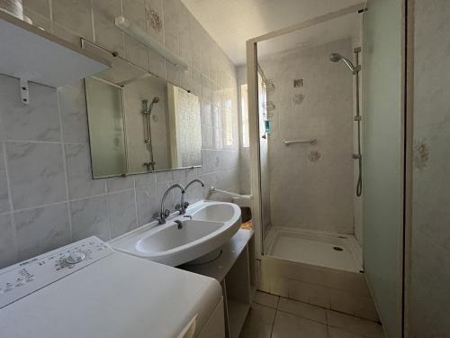 une salle de bain blanche avec un lavabo et une douche dans l'établissement Charmant T3 climatisé en RDC, terrasse fleurie, idéal famille, 6P, proche plage, parking inclus - FR-1-799-18, au Barcarès