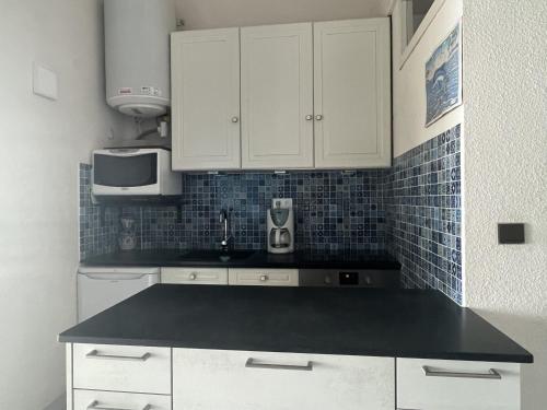 une cuisine avec des armoires blanches et un comptoir noir dans l'établissement Appartement T2 Cabine Mezzanine avec Parking à 50m de la Plage - FR-1-799-23, au Barcarès