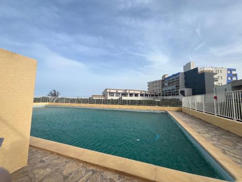 une piscine sur le côté d'un immeuble dans l'établissement Spacieux T3 au Barcarès avec piscine, ascenseur, parking sécurisé, animaux admis - FR-1-799-8, au Barcarès