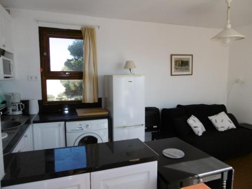 Il dispose d'une cuisine et d'un salon avec un canapé et un réfrigérateur. dans l'établissement Charmant T2 au Barcarès - Accès plage - 4P - Terrasse - Parking - FR-1-799-10, au Barcarès