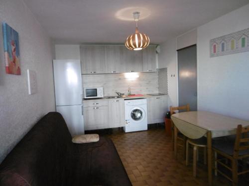 Il comprend une cuisine équipée d'un réfrigérateur blanc et d'une table. dans l'établissement Le Barcarès - Résidence Front de Mer - T2 Alcôve RDC - 4 Pers - Grande Plage - Parking Inclus - FR-1-799-11, au Barcarès