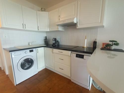 une cuisine blanche avec une machine à laver à l'intérieur dans l'établissement Le Barcarès : T2 tout confort avec parking privé, animaux admis - FR-1-799-44, au Barcarès