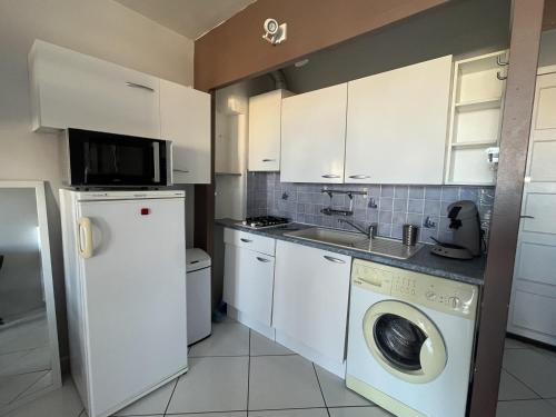 une cuisine avec des armoires blanches et une laveuse et une sécheuse dans l'établissement Studio confortable 3P avec piscines et parking public - Le Barcarès - FR-1-799-22, au Barcarès