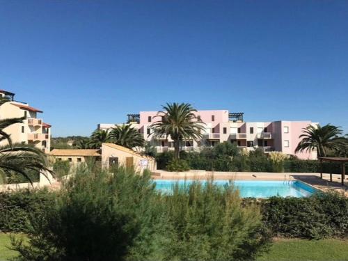 une piscine devant un immeuble avec des palmiers dans l'établissement Saint Cyprien T2 proche plage avec piscine et parking - FR-1-732-80, à Saint-Cyprien