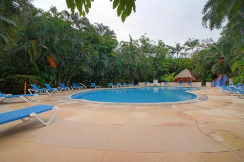 a swimming pool with chairs and trees in the background at Condominio con Alberca en la Zona Hotelera Puerto Vallarta in Puerto Vallarta