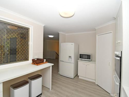 a kitchen with a white refrigerator and a counter at Kingfisher by the Sea in Toogoom