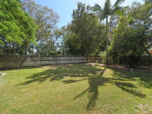 a large yard with a fence and a palm tree at Kingfisher by the Sea in Toogoom