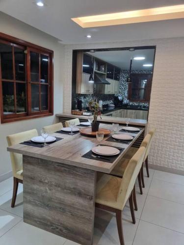 a kitchen with a large wooden table with chairs at Casa Cond Ocean House Camboinhas Pé na Areia 4qts in Niterói