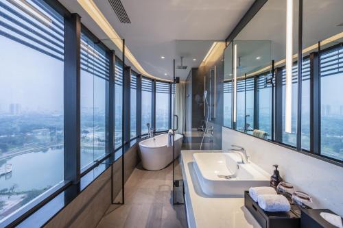 a bathroom with a tub and a sink and windows at Fraser Residence Hanoi in Hanoi