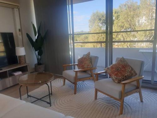 a living room with two chairs and a coffee table at Spacious Apartment Oasis in Bankstown