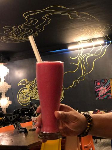 a person holding a pink drink with a straw at Cafe Moto Hostel in Puerto Princesa City