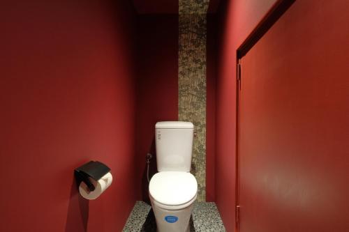 a bathroom with a white toilet in a red wall at 国際通りまで車で5分 那覇空港まで車で8分 最大15名 As bld in Makishimachi