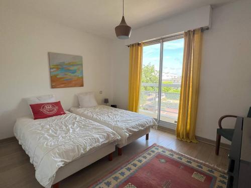 une chambre avec deux lits et une grande fenêtre dans l'établissement La Baule: Bel appartement à 250m de la plage et des commerces - FR-1-392-238, au Pouliguen