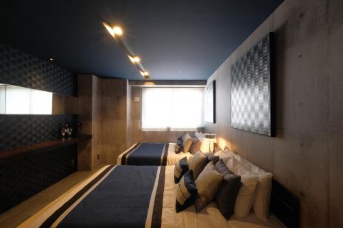 a bedroom with two beds and a window at 国際通りまで車で5分 那覇空港まで車で8分 最大15名 As bld in Makishimachi