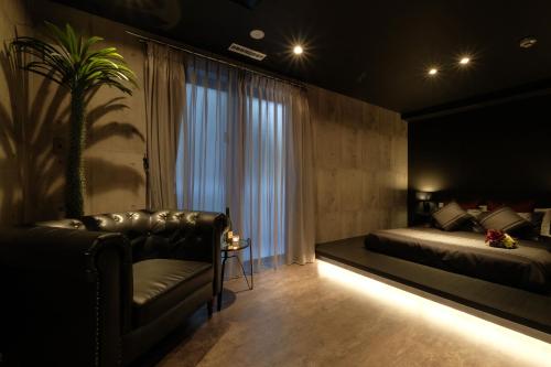 a bedroom with a bed and a chair and a window at 国際通りまで車で5分 那覇空港まで車で8分 最大15名 As bld in Makishimachi