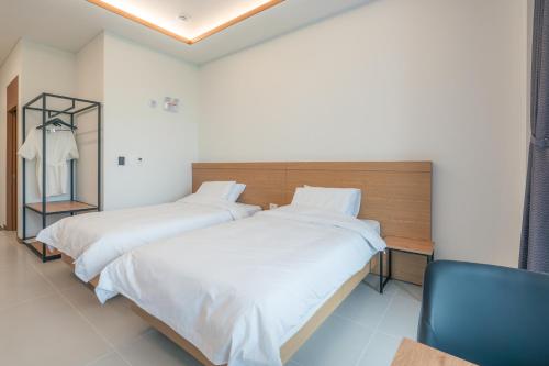two beds in a room with a chair at Dongho Beach Hotel in Gochang 
