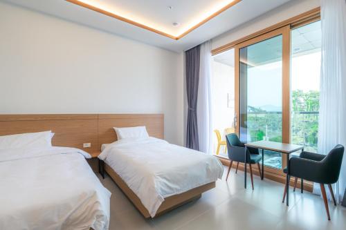 a bedroom with two beds and a desk and a window at Dongho Beach Hotel in Gochang 