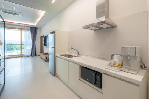 a white kitchen with a sink and a microwave at Dongho Beach Hotel in Gochang 