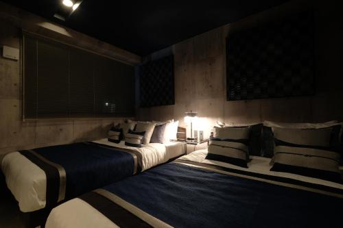 a bedroom with two beds with pillows at 国際通りまで車で5分 那覇空港まで車で8分 最大15名 As bld in Makishimachi