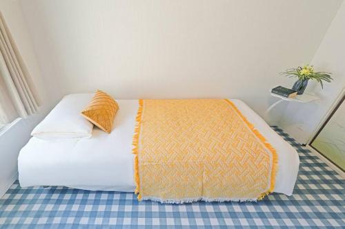 a bedroom with a white bed with an orange blanket at Meek House 难波6分钟车程&最近电车站1分钟&奈良京都一小时&大型超市旁&安静生活区 in Osaka