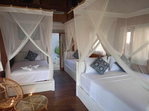 吉利阿尔Bintang Tiga Bungalows Gili Air的一间卧室配有两张床、窗帘和桌子
