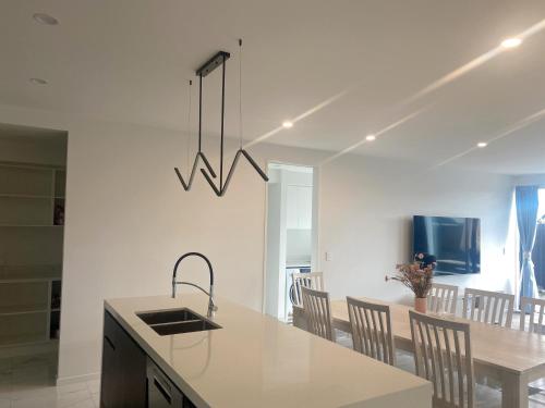 a kitchen with a sink and a table with chairs at Modern luxury four bedroom house in Christchurch