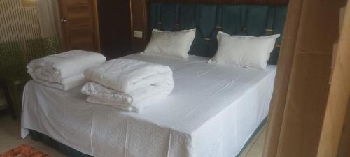 un letto bianco con lenzuola e cuscini bianchi di Kanti Resort a Phata