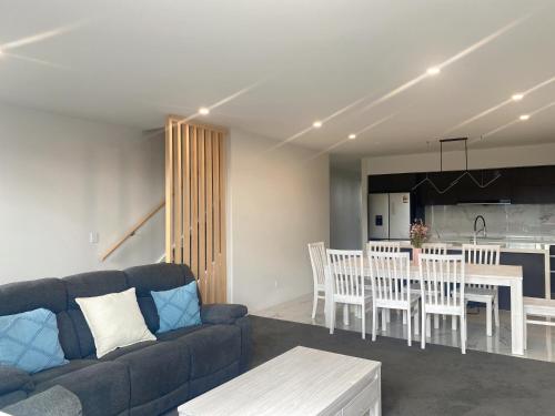 a living room with a couch and a table and a kitchen at Modern luxury four bedroom house in Christchurch