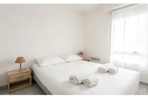 une chambre avec un lit blanc avec des serviettes dessus dans l'établissement Le Botéro-T3 agréable, 2 chambres, balcon & garage, à Dinard