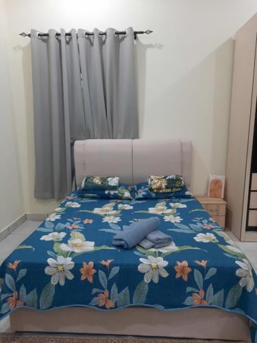 a bed with a blue blanket with flowers on it at Homestay sekamat ,kajang in Kajang