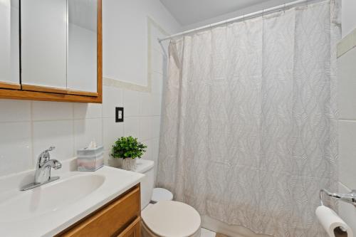 a bathroom with a white shower curtain and a toilet at The Commuter Dream Apartment close to NYC in Newark