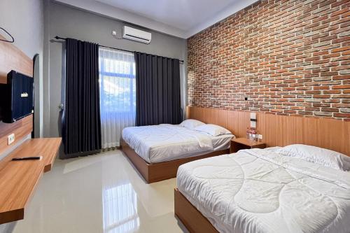 two beds in a room with a brick wall at RedDoorz Plus at New Favour Hotel Gunung Dempo in Bumiagung