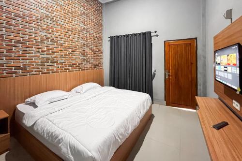 a bedroom with a bed and a brick wall at RedDoorz Plus at New Favour Hotel Gunung Dempo in Bumiagung