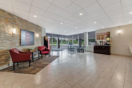 a lobby with red chairs and tables and a brick wall at Red Roof Inn & Suites Wilkesboro in Wilkesboro