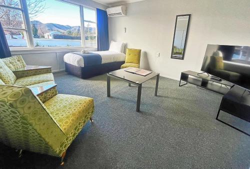 a living room with a couch and a bed and a tv at Kurow Motel in Kurow