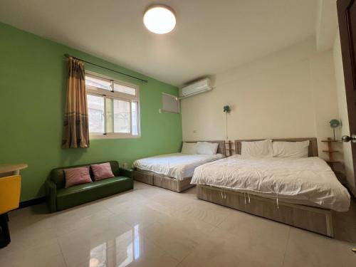 a bedroom with two beds and a couch and a window at 市區背包客棧 有套房可包棟 in Jincheng